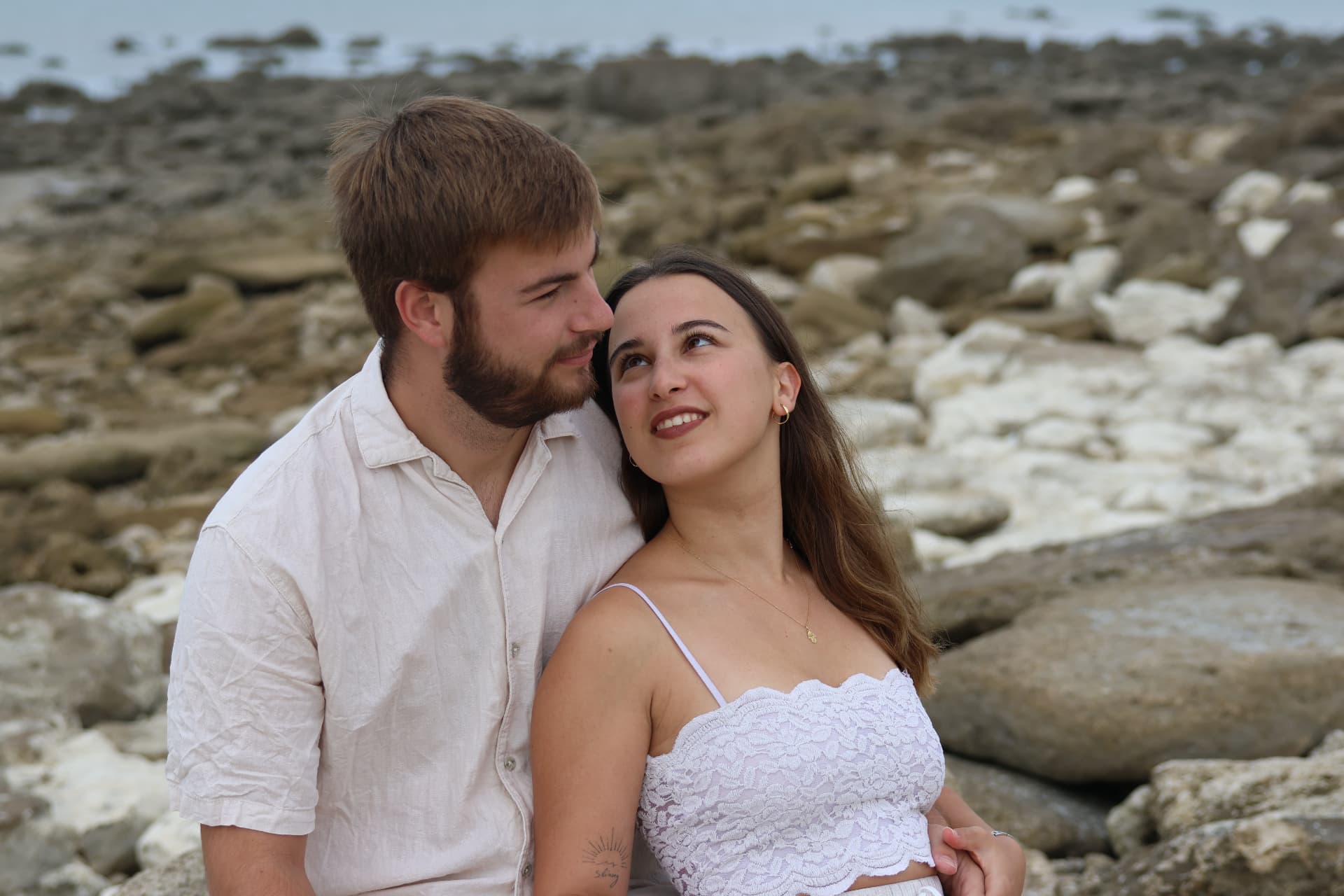 Couple assis sur les rochers du littoral, ambiance douce et nuageuse