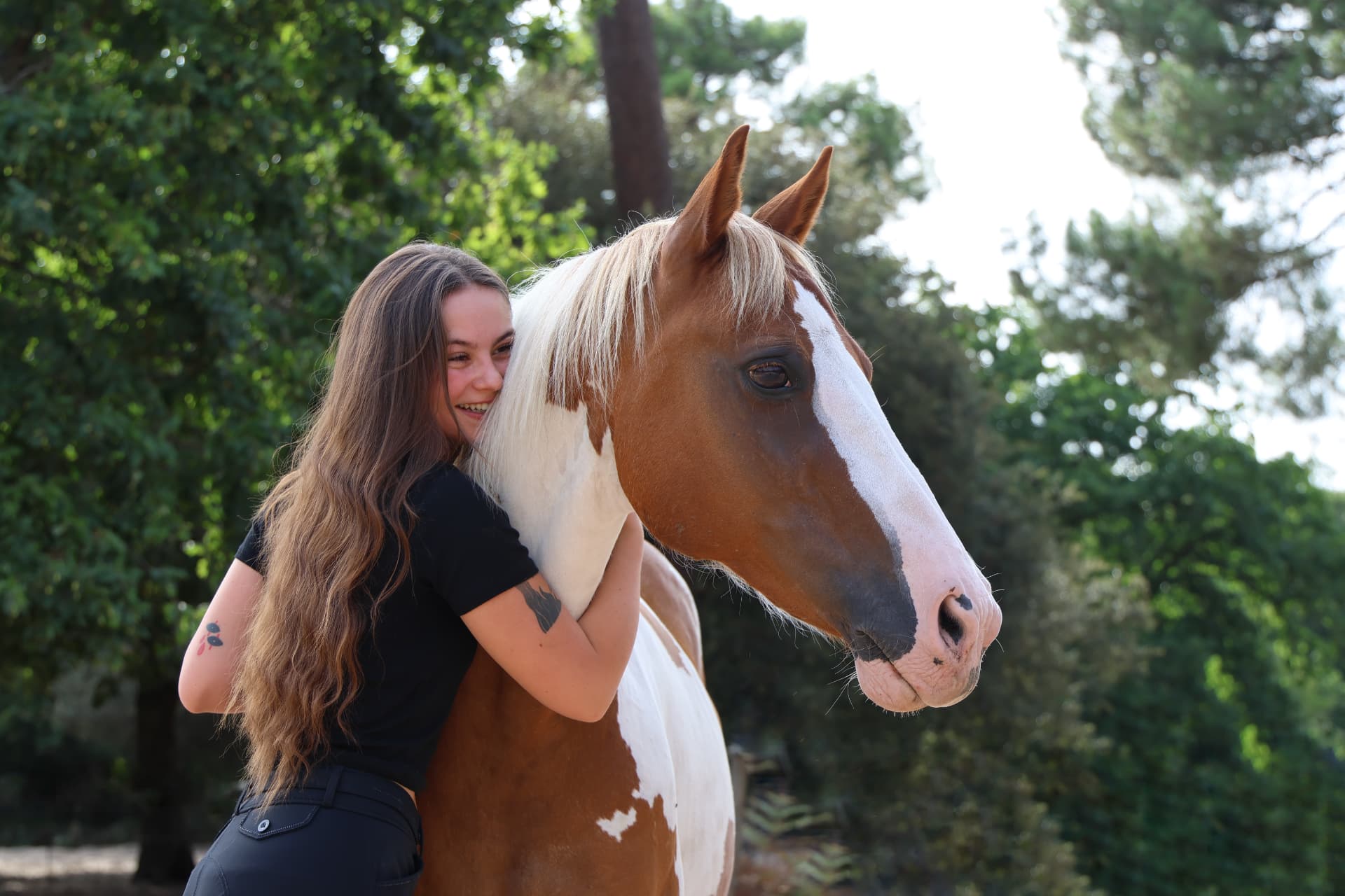 Cavalière enlaçant son cheval pie en lumière naturelle, séance équestre en Charente-Maritime