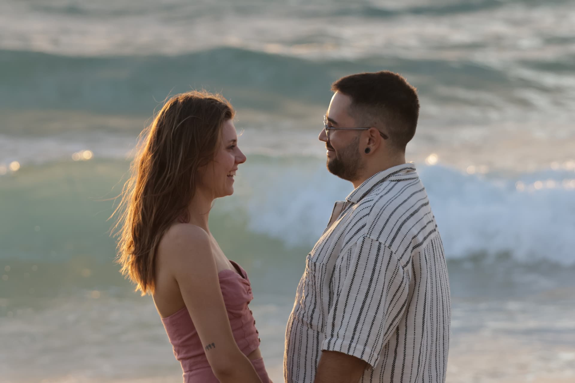 Couple face à face sur la plage, vagues de l'océan en arrière-plan
