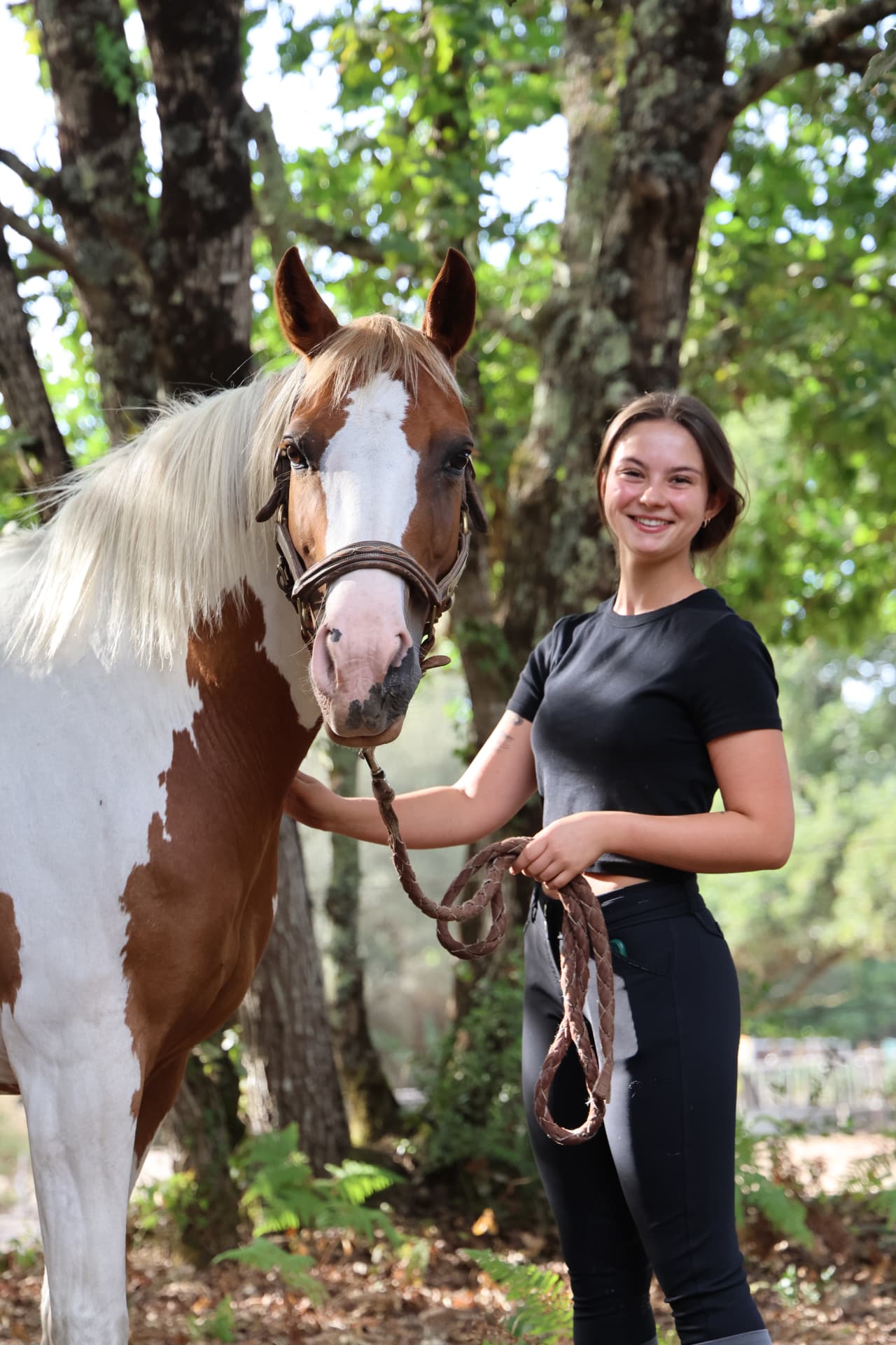 Portrait d'une cavalière riant aux côtés de son cheval pie